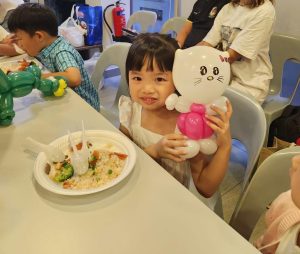 girl holding a hello kitty balloon animal in a birthday party